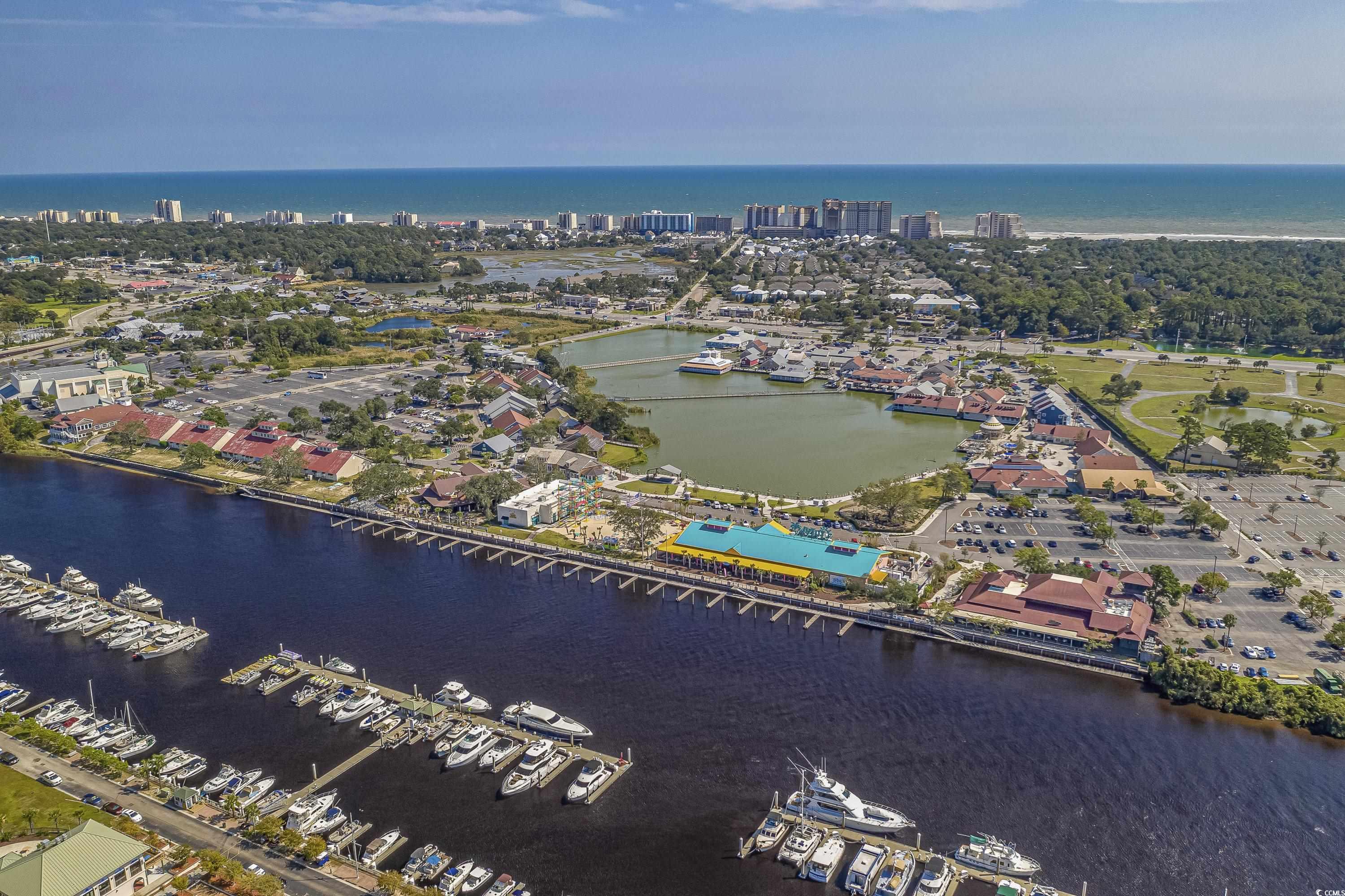 Aerial view of a coastal marina with boats, waterfront buildings, and the ocean beyond.