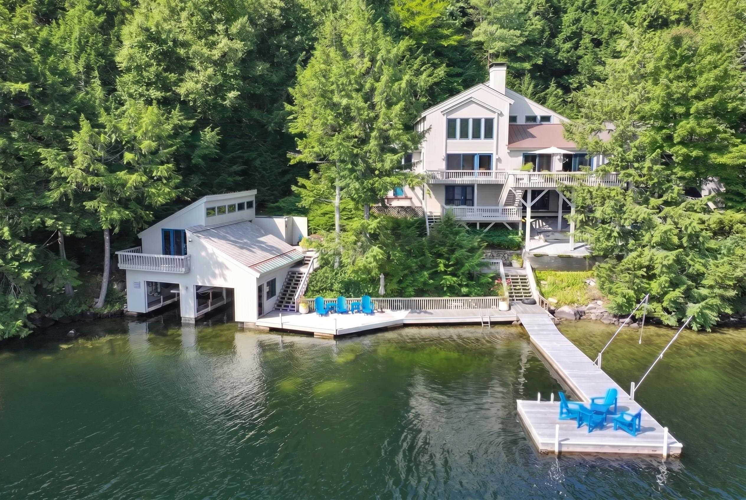 A wooded waterfront home with expansive decks, a separate boathouse, and a long dock.