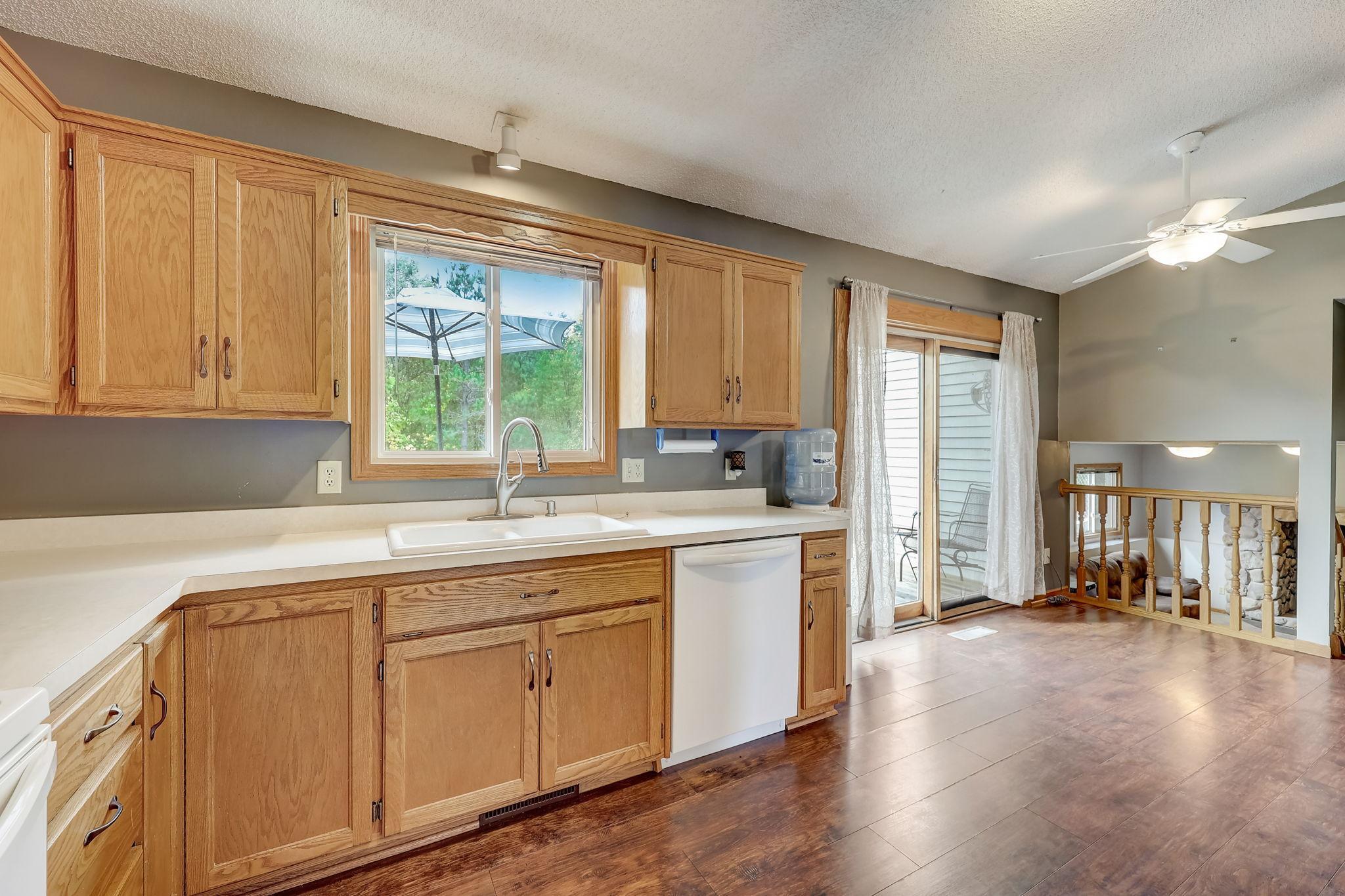 Kitchen with honey-colored cabinets, a sink beneath the window, and a sliding glass door to the patio.