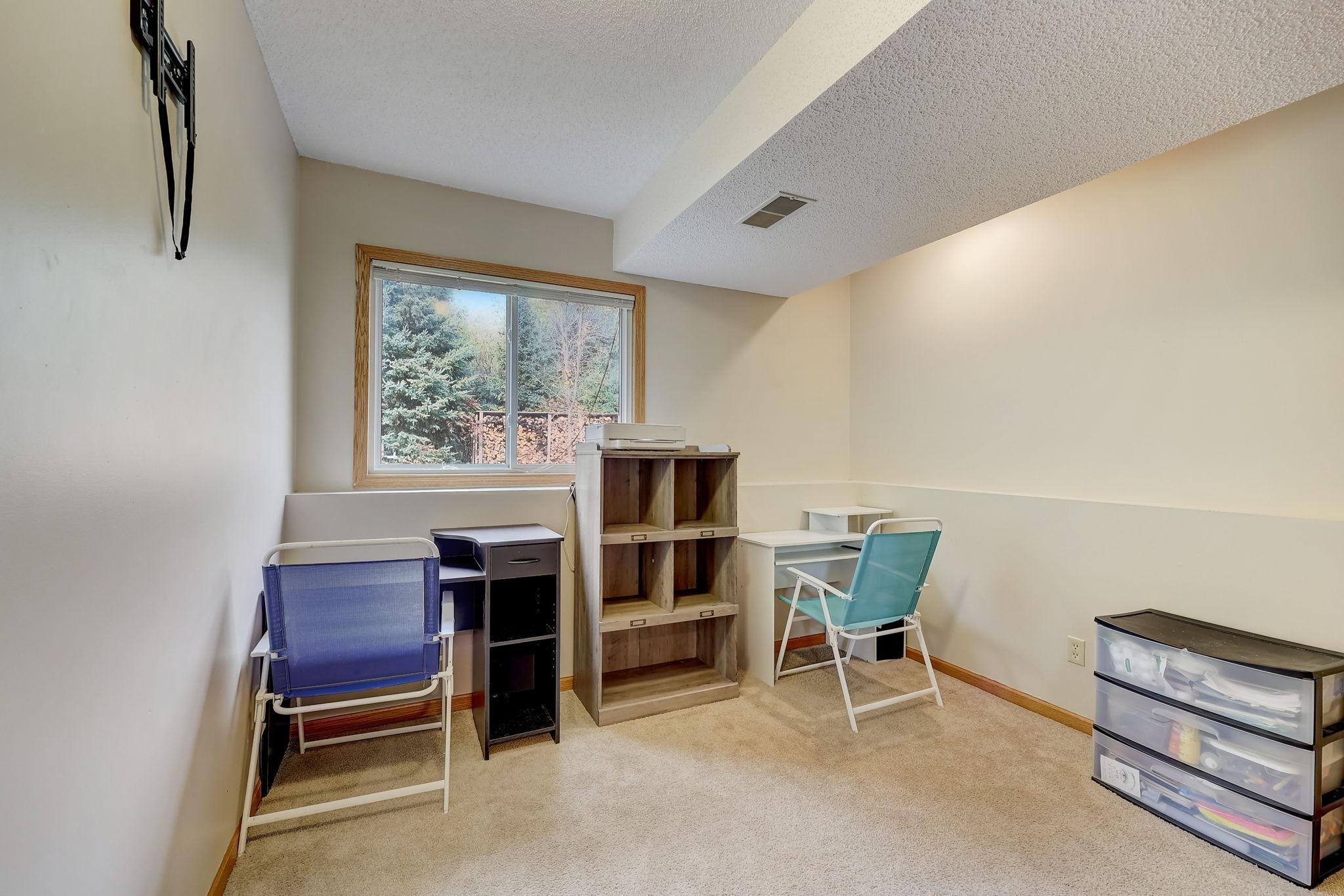 Furnished office with a large window, shelving, desks, and folding chairs.