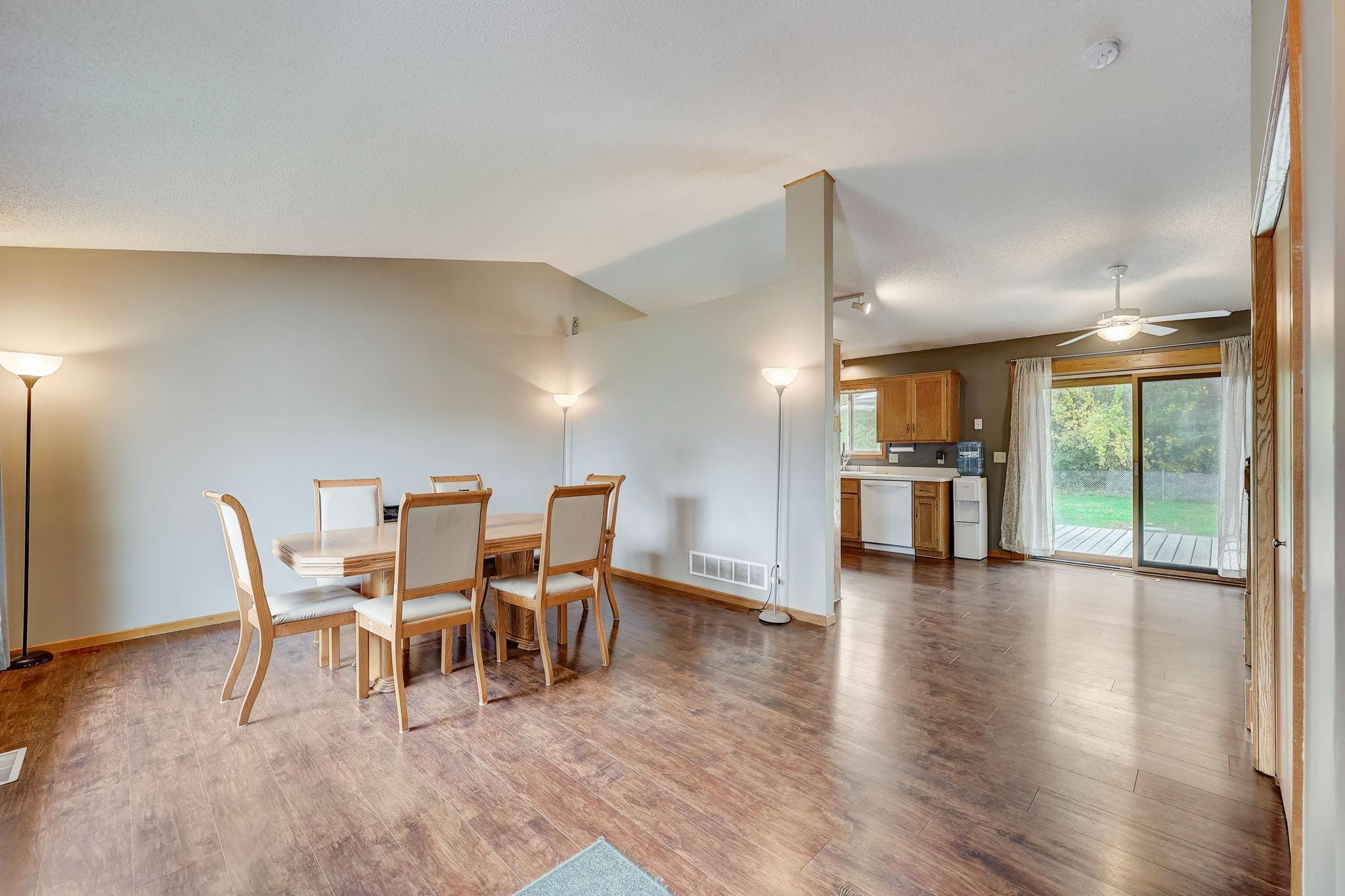 Dining area with a wooden table, open kitchen, and sliding glass door to the backyard.