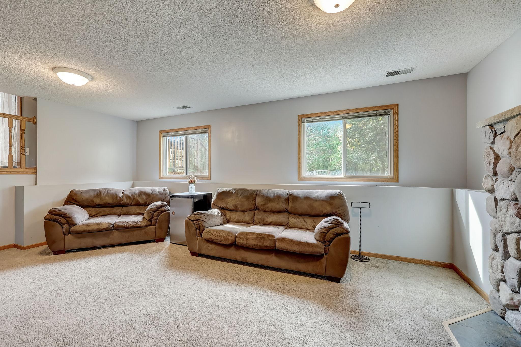 Living room with two brown sofas, beige carpet, and a stone fireplace.