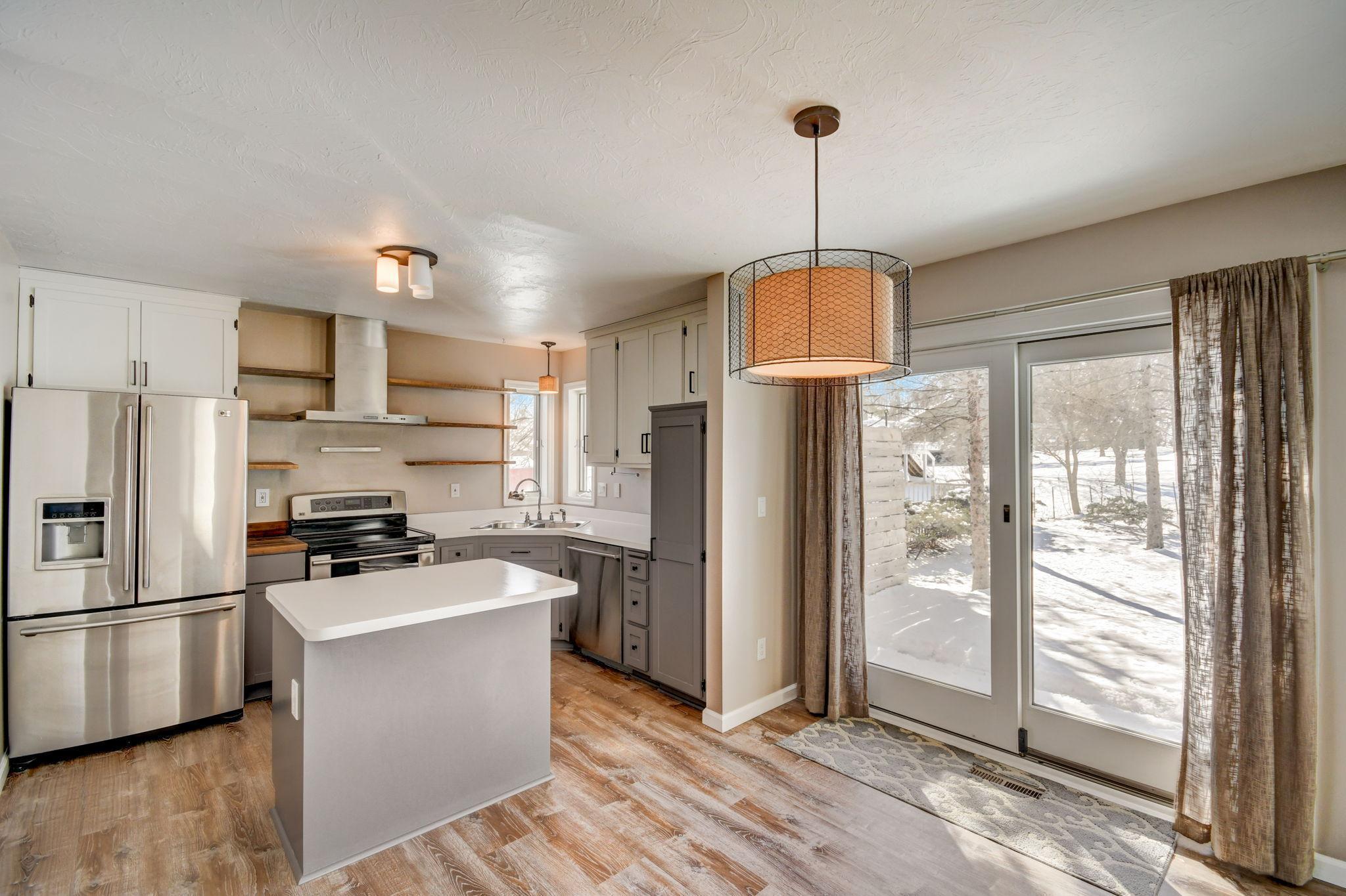 Kitchen with a white island, stainless steel appliances, and sliding doors opening to a snowy yard.