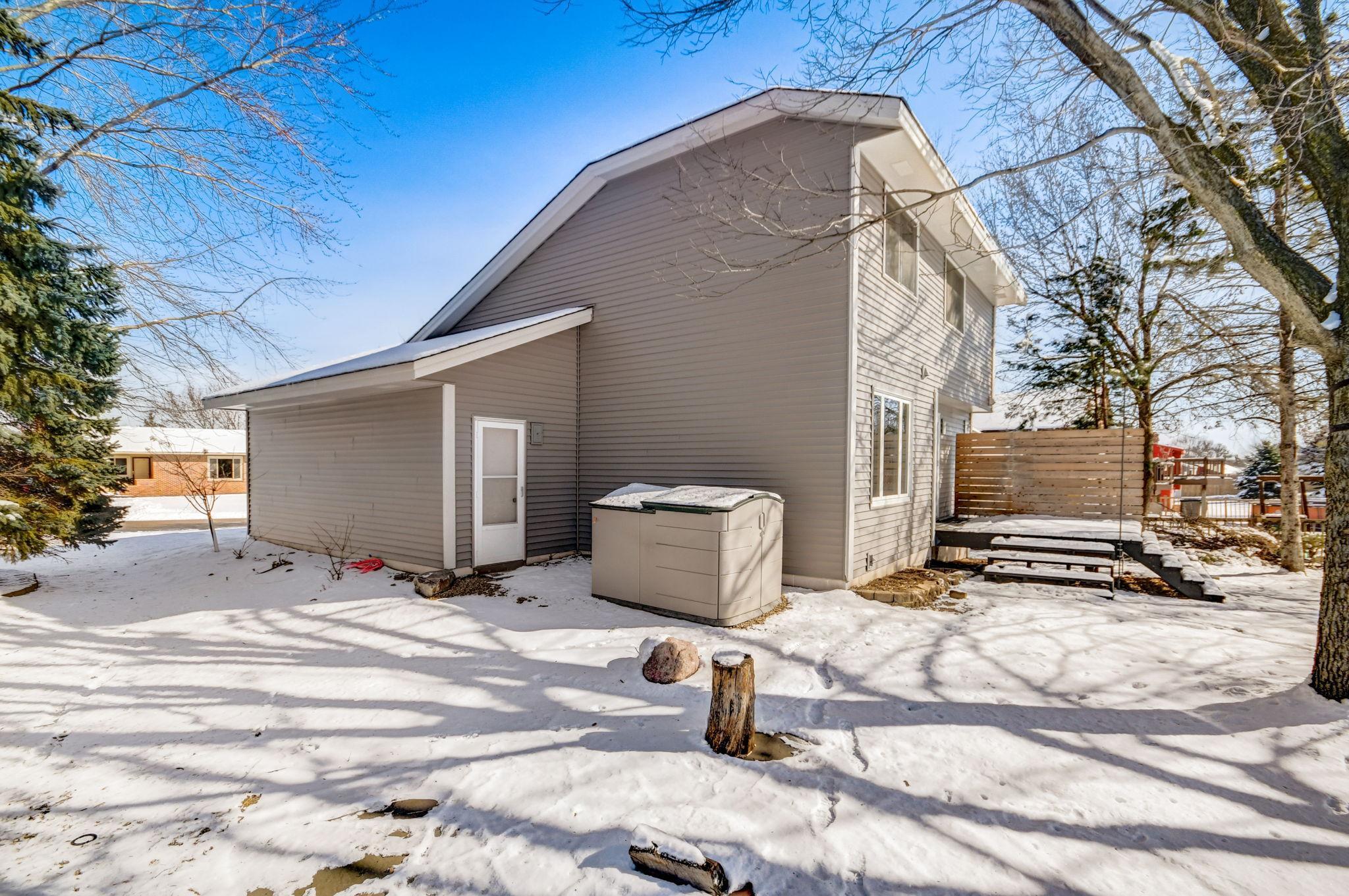 Rear of a gray two-story house with a raised privacy-fenced deck and snow-covered yard.
