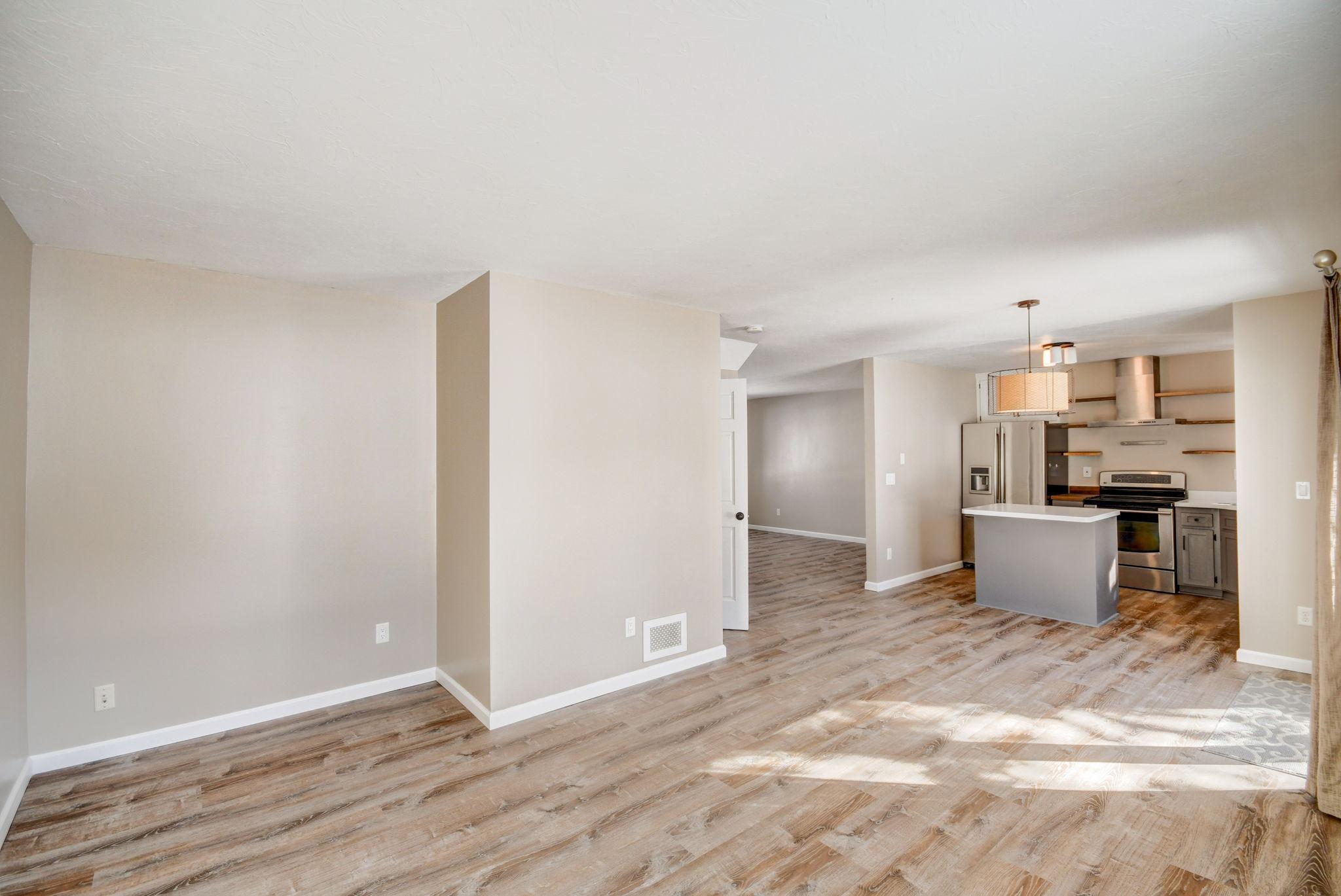 Open-plan kitchen and dining area with a gray island, stainless appliances, and wood-look flooring.