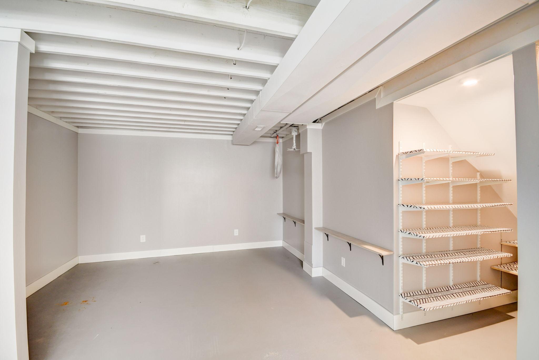 Basement storage area with exposed ceiling joists and built-in wire shelving.
