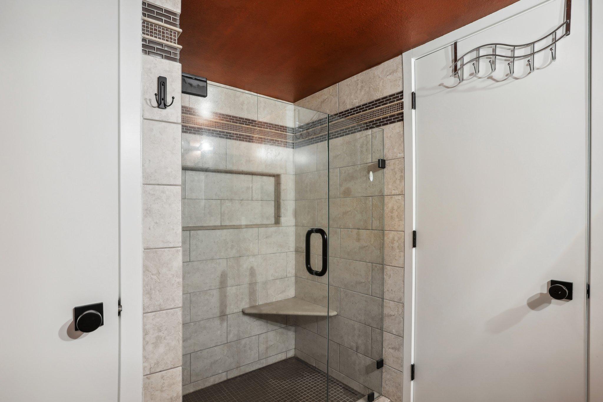 Tiled walk-in shower with glass doors, a built-in bench, and a recessed wall niche.