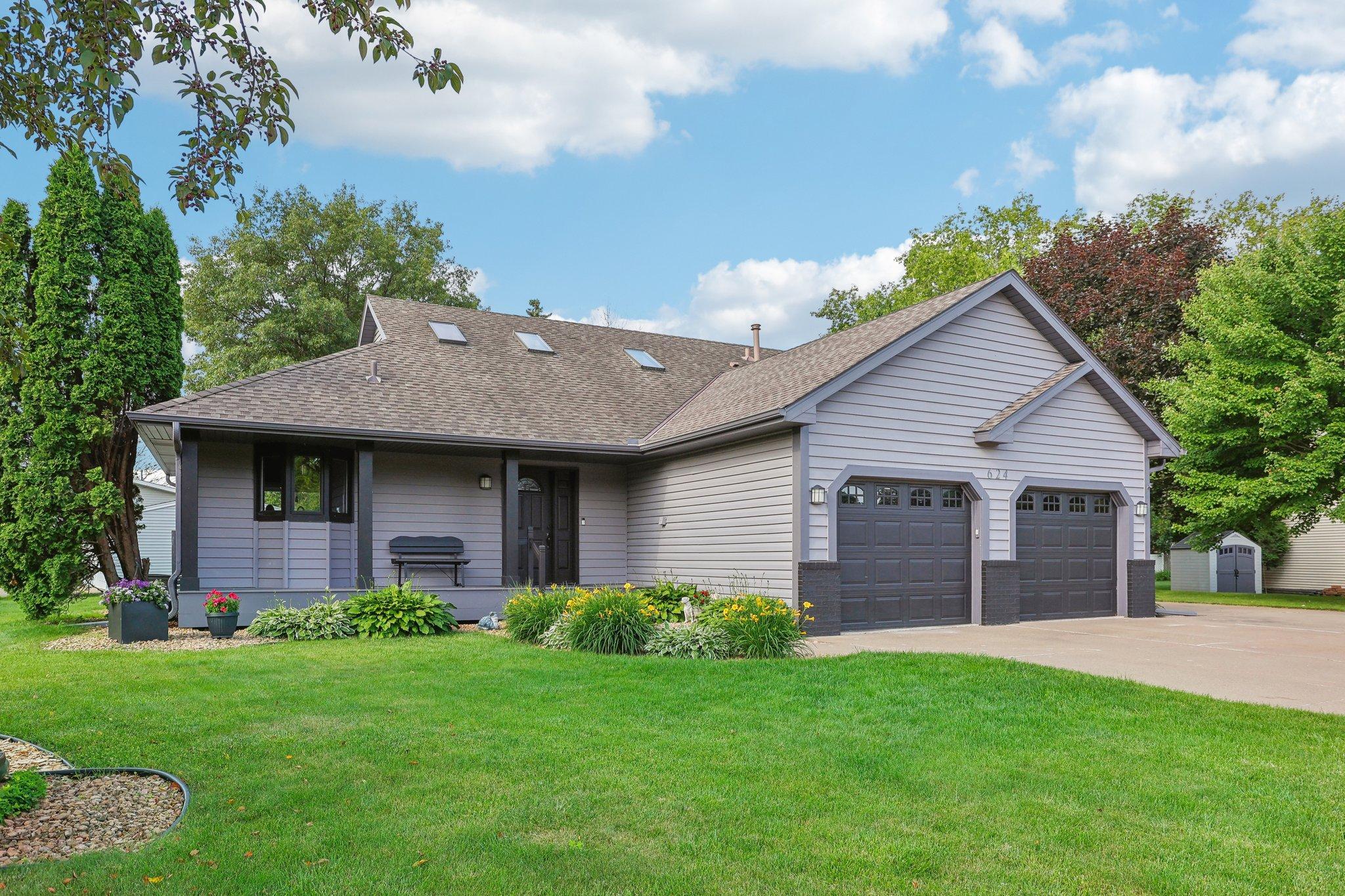 Gray single-story house with two-car garage, skylights, and landscaped front lawn.