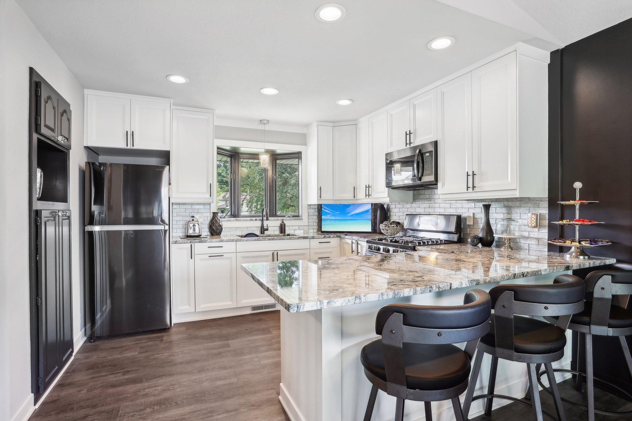 Updated kitchen with white cabinets, stainless appliances, and a large stone island with bar seating.