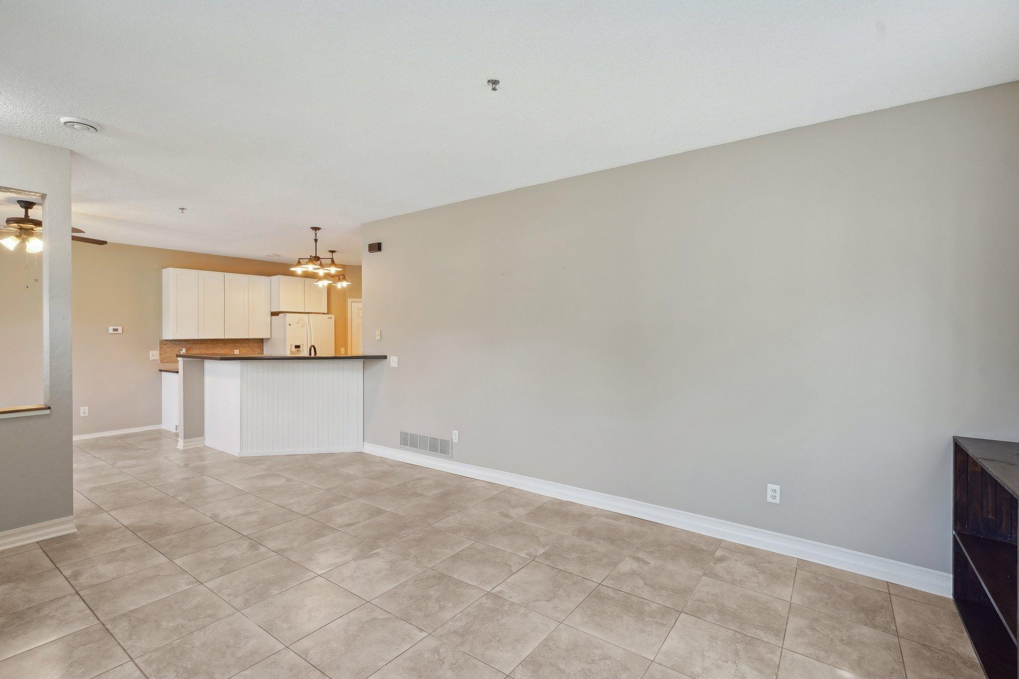 Open dining area with beige tile floors and a white kitchen peninsula.