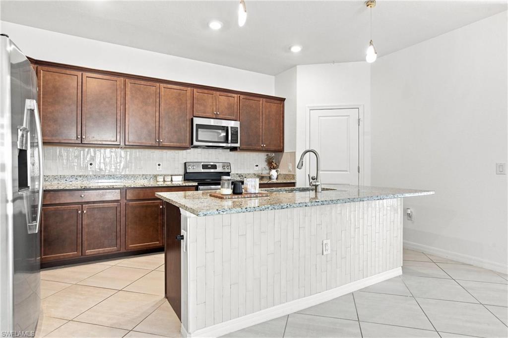 Kitchen with dark wood cabinets, granite counters, stainless appliances, and a large island.