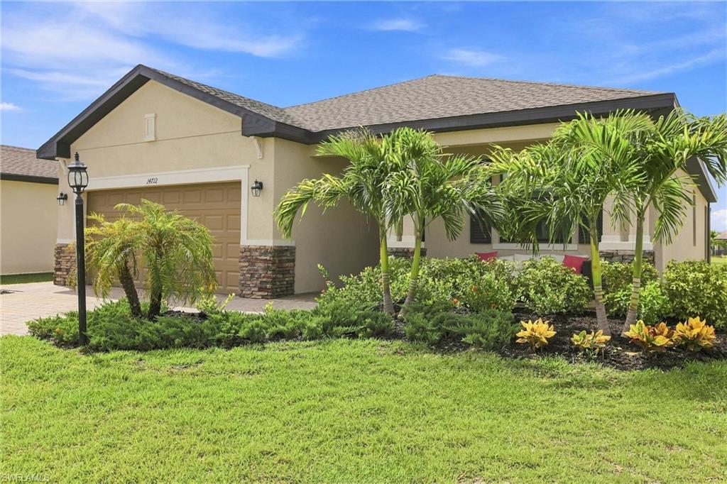 Single-story beige home with a double garage, palm trees, and landscaped front garden.