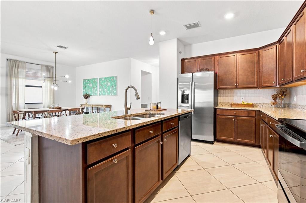 Kitchen with a granite island, dark wood cabinets, stainless steel appliances, and an adjoining dining area.