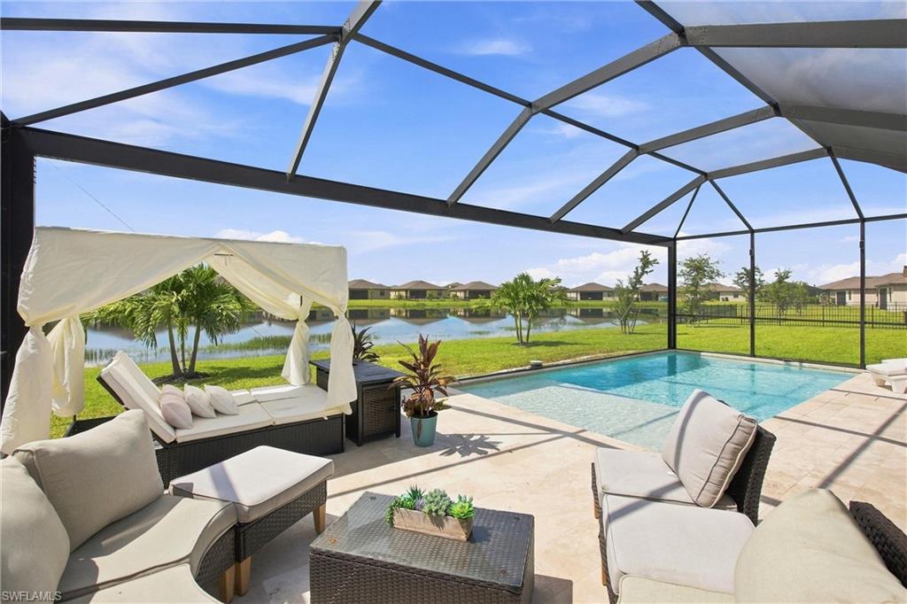 Screened pool lanai with furnished patio seating and a lake view.