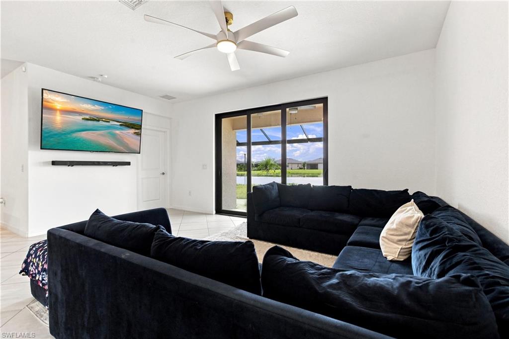 Living room with a large dark sectional, wall-mounted TV, and sliding glass doors overlooking the yard.