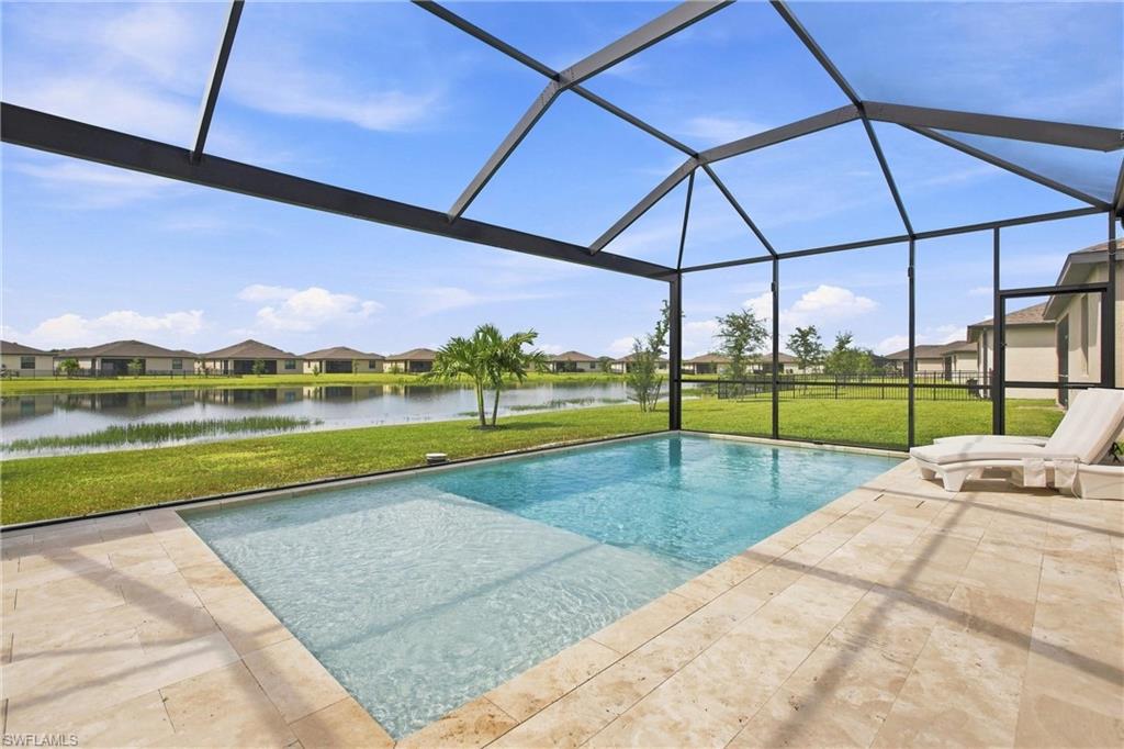 Screened backyard pool with a shallow sun shelf, tiled patio, and lake view.