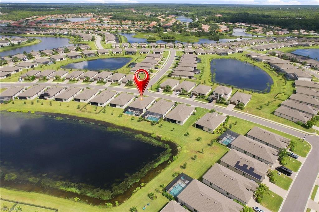 Aerial view of the marked home in a neighborhood surrounded by ponds and homes with screened pools.