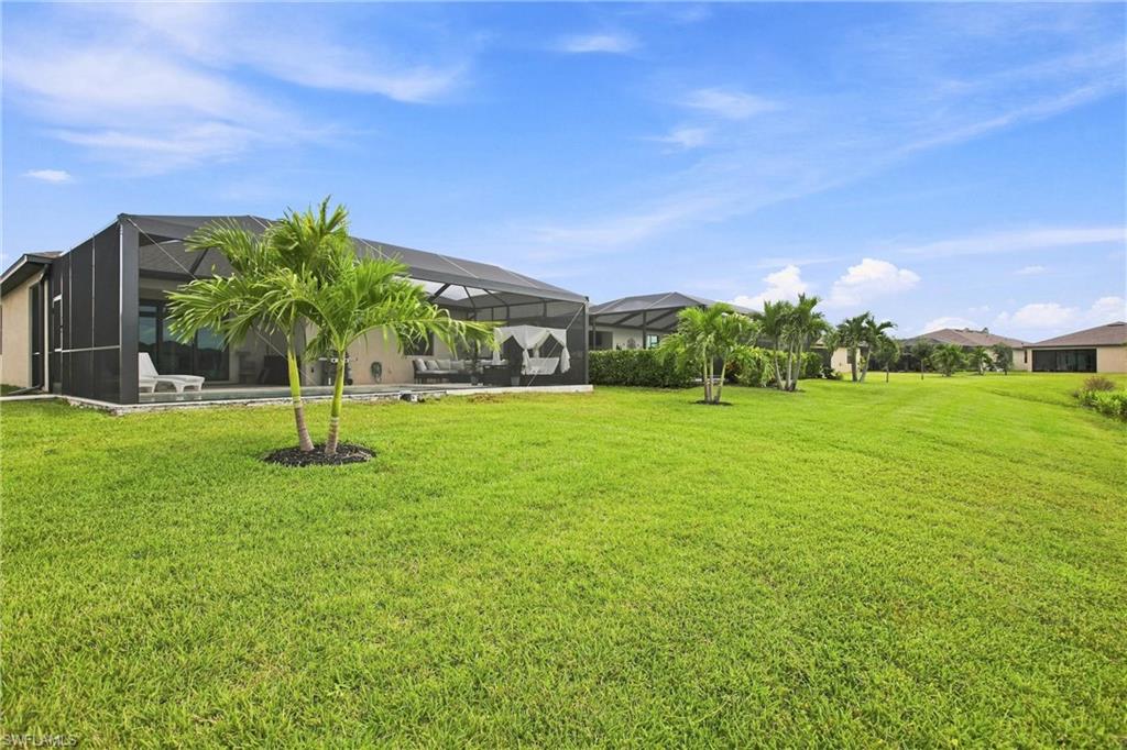 Home with a screened lanai and palm trees across a broad green lawn.