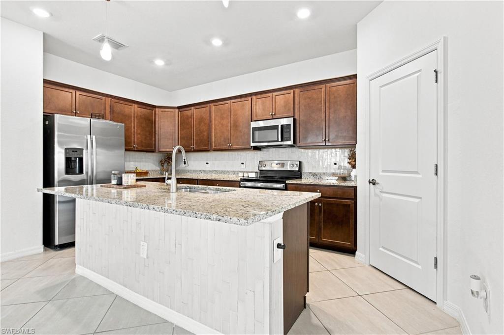 Kitchen with dark wood cabinets, stainless steel appliances, and a large granite-topped island.