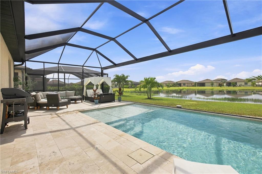 Pool and screened lanai with outdoor seating overlooking a lake.