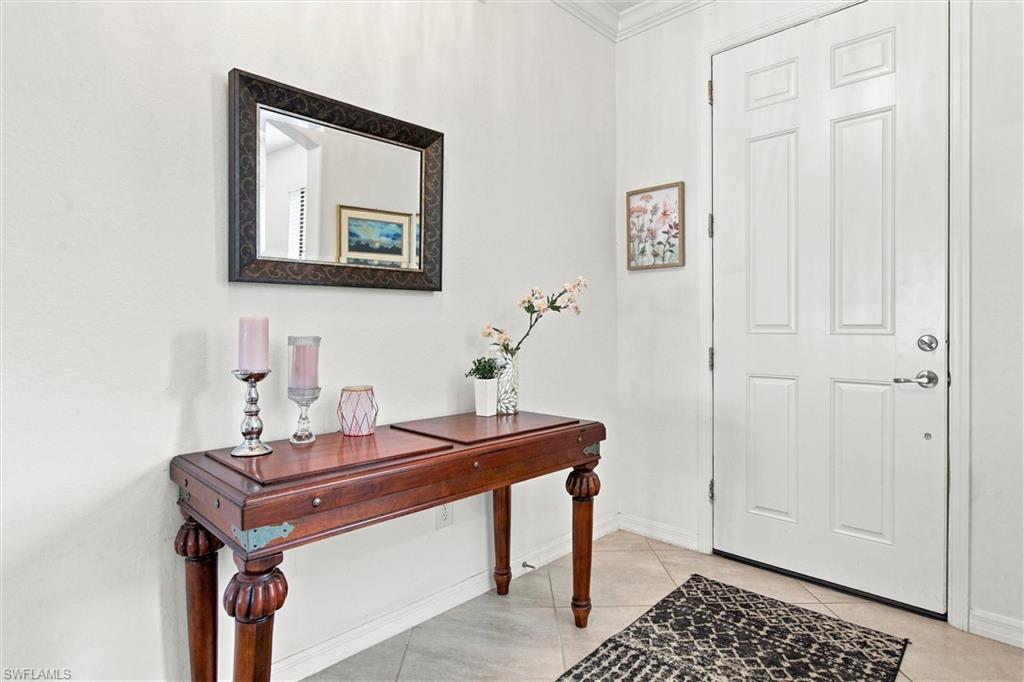 Entry foyer with a white paneled door, dark wood console table, framed mirror, and patterned rug.