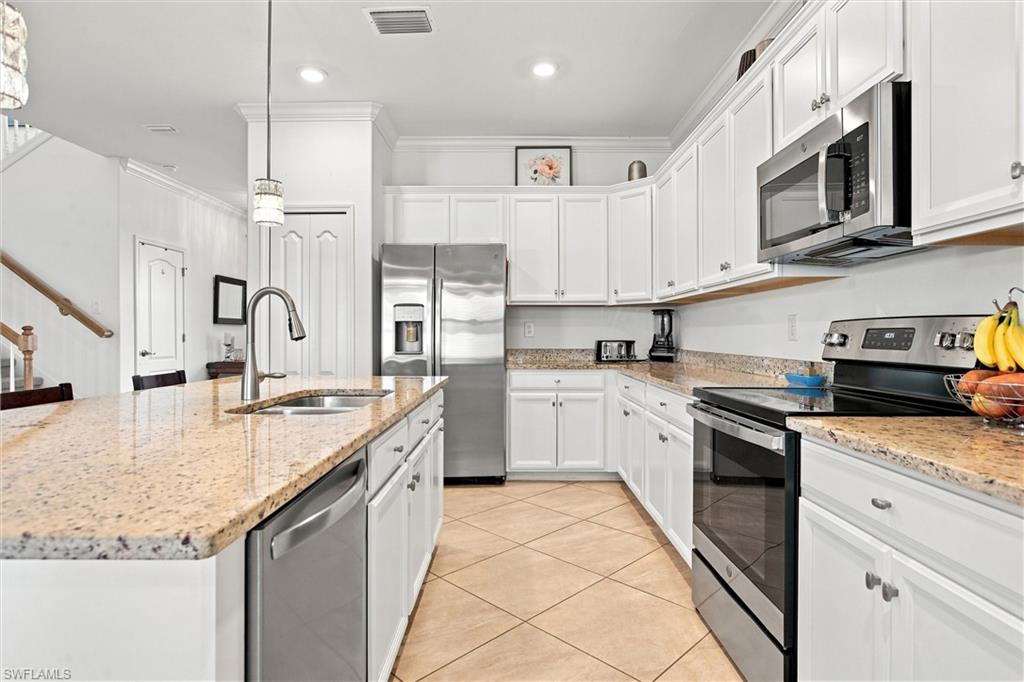 Kitchen with white cabinetry, granite counters, a large island, and stainless-steel appliances.