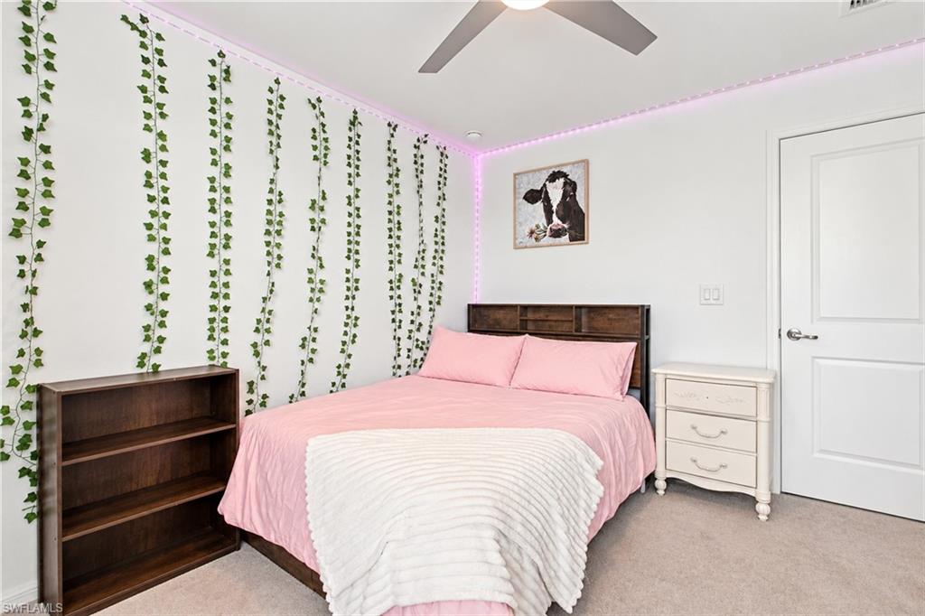 Bedroom with a pink bed, trailing wall vines, and pink LED lighting.