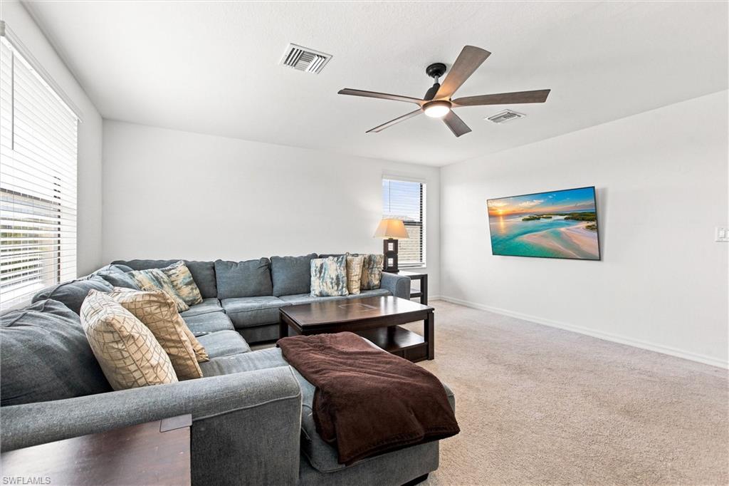 Living room with a gray sectional, dark wood coffee table, and ceiling fan.