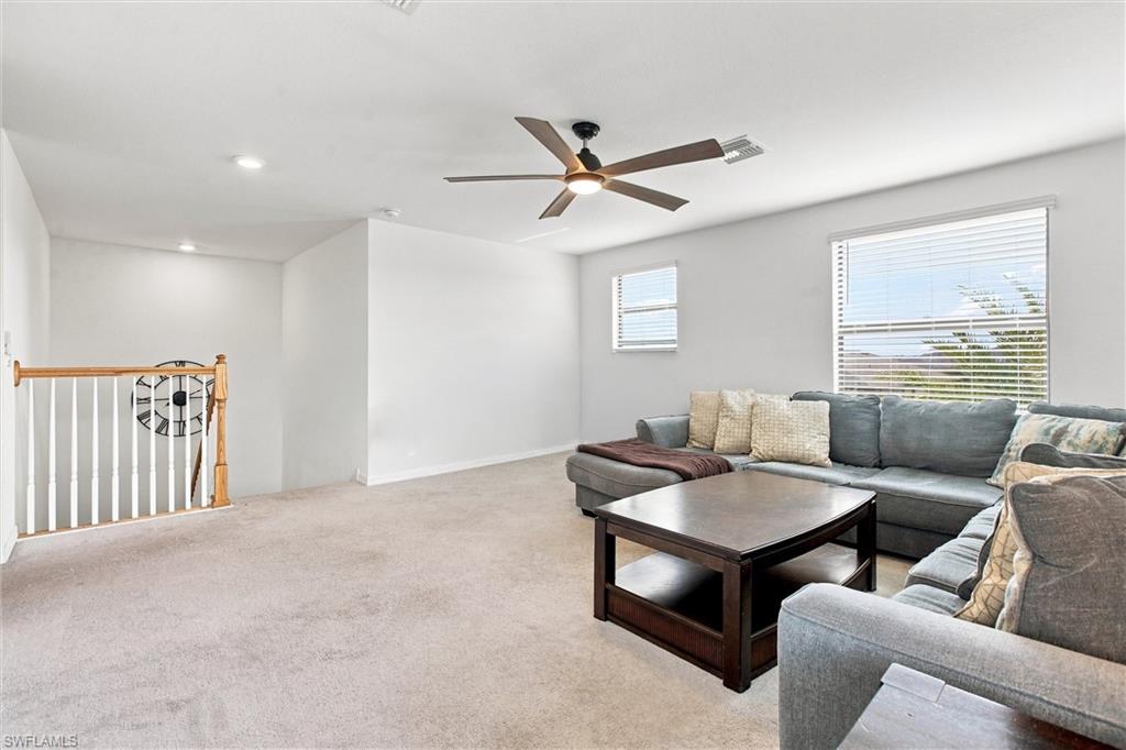 Upstairs living room with gray sectional sofas, beige carpet, and a ceiling fan.