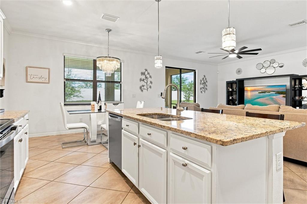 Open-plan kitchen with a large granite island and sink, looking toward the dining area and living room.