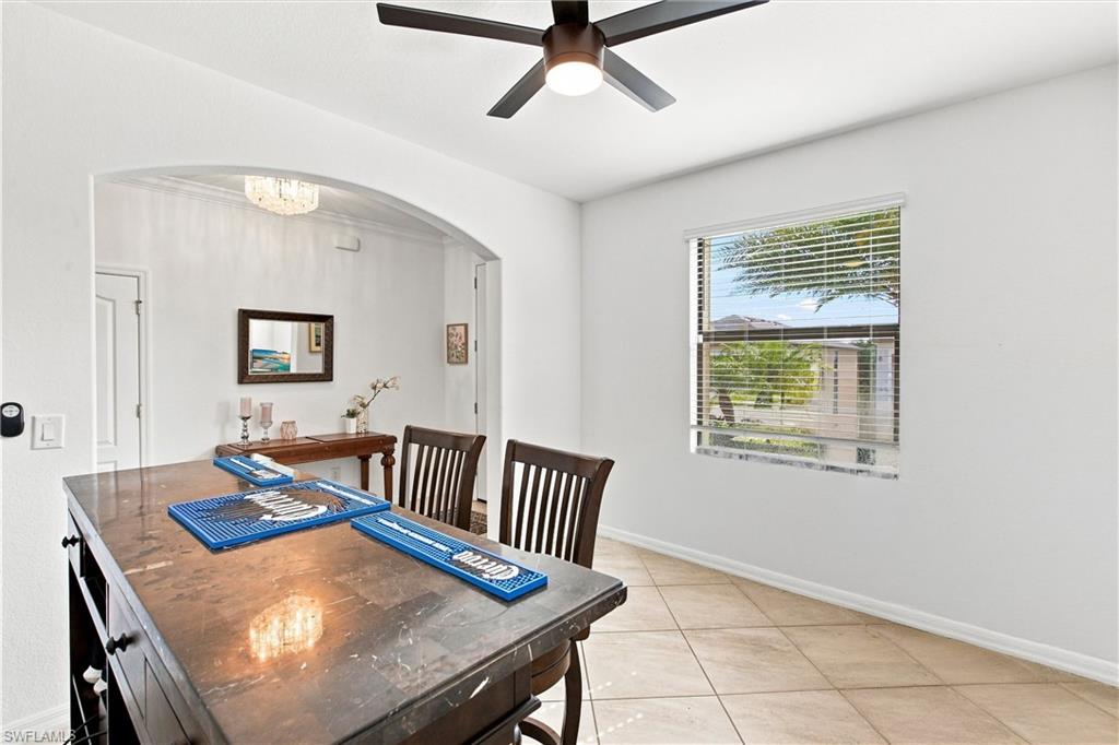 Dining area with a dark wood table, blue runners, tiled floors, and an arched opening.