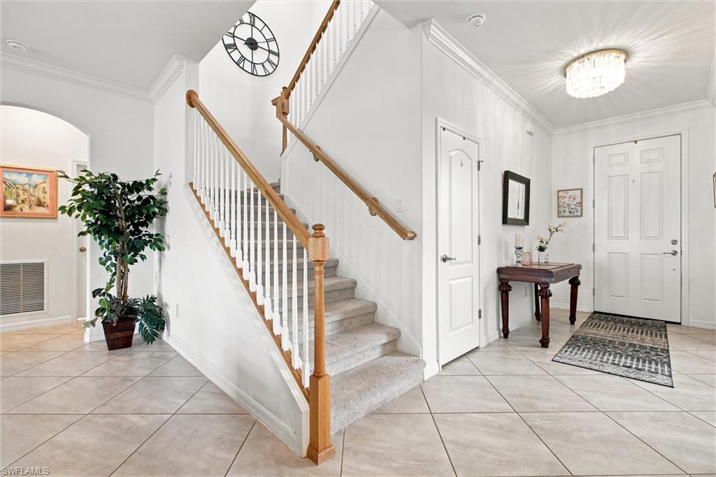 Home foyer with a carpeted staircase, wood handrails, tiled floor, and console table beside the front door.