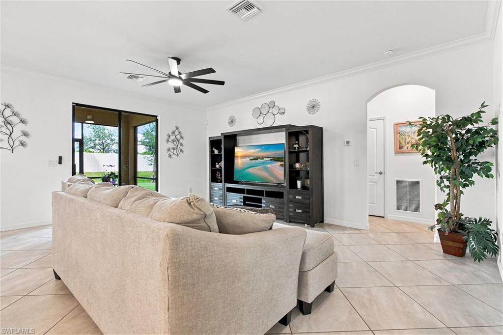 Living room with a beige sectional, black entertainment center, and sliding doors to a fenced backyard.