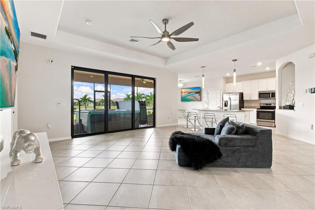 Living room and kitchen with sofa, tile floors, and sliding doors to an outdoor spa.