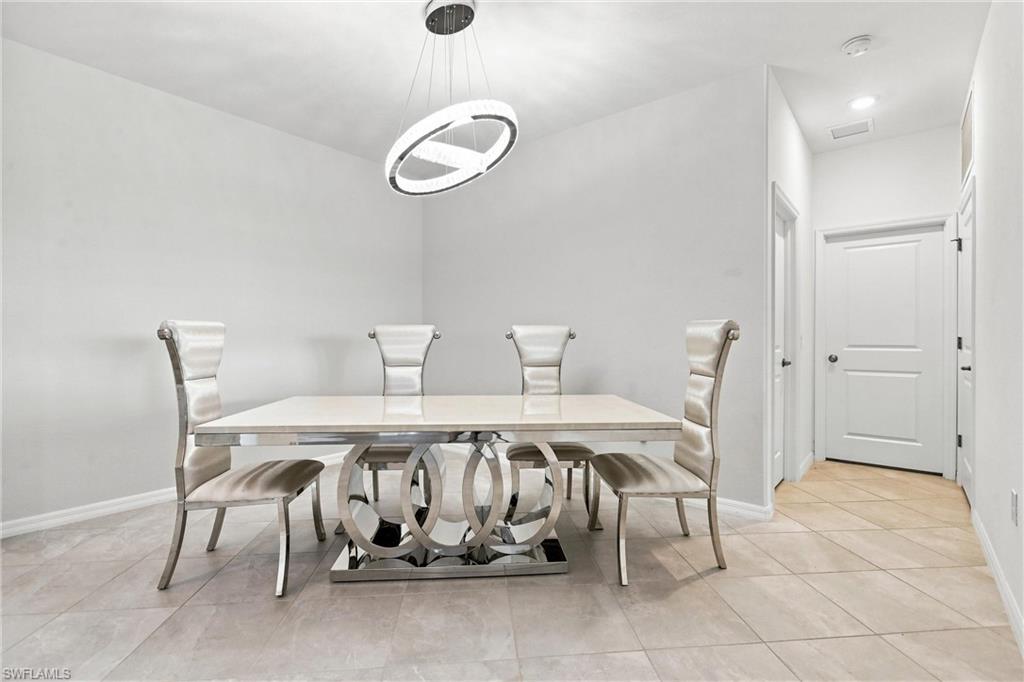 Dining room with a sculptural metal-base table, four upholstered chairs, and a ring pendant light.