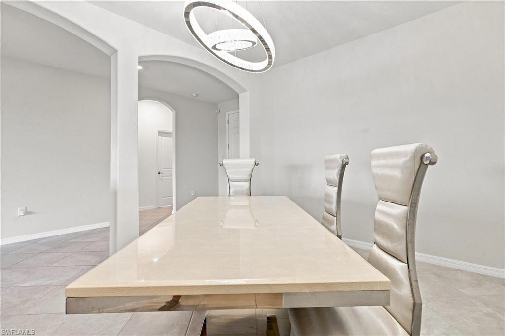Dining room with a glossy cream table, sculptural chairs, and a modern ring chandelier.