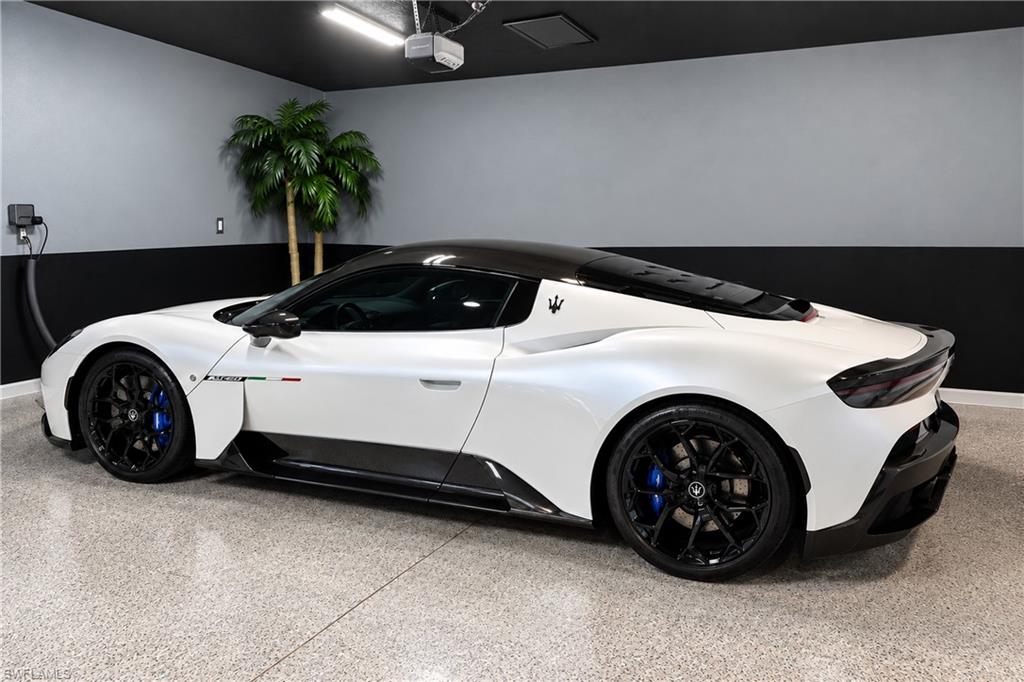 Finished garage with a white Maserati sports car, black-and-gray walls, and a speckled floor.