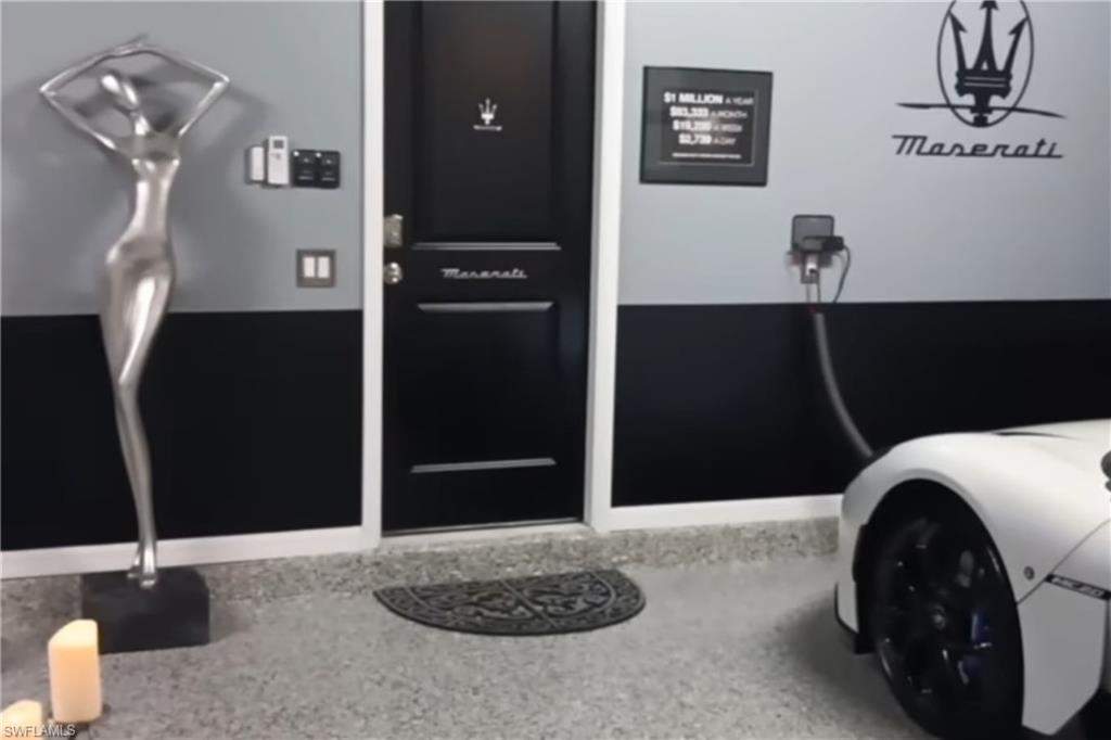 Maserati-themed garage with a white sports car, polished floor, and silver sculpture.