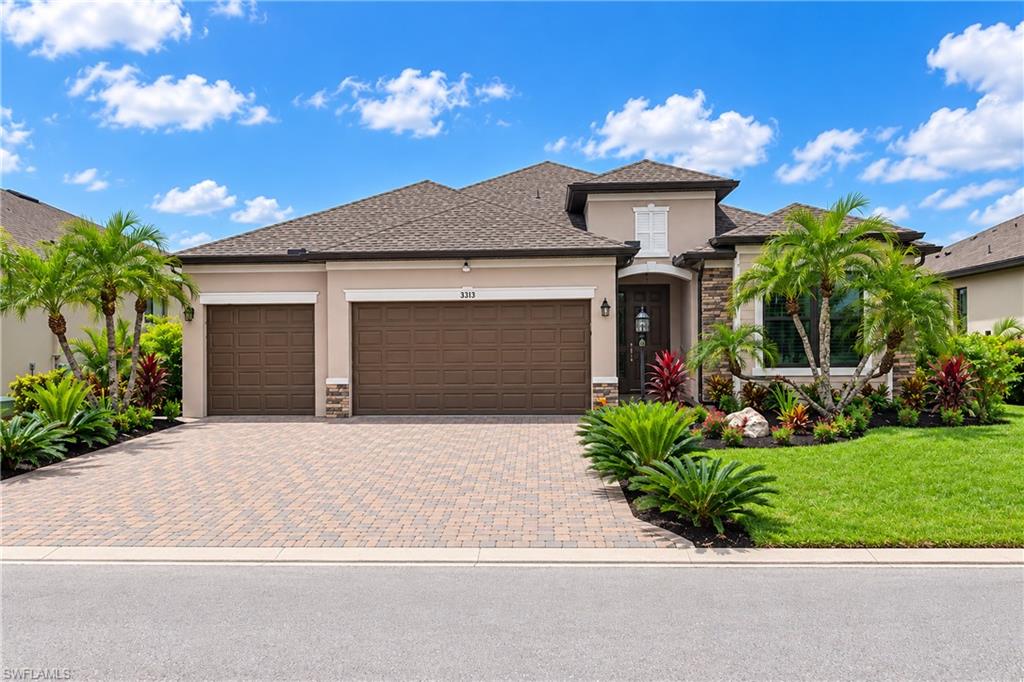 Two-story home with a three-car garage, palm landscaping, and a broad paver driveway.