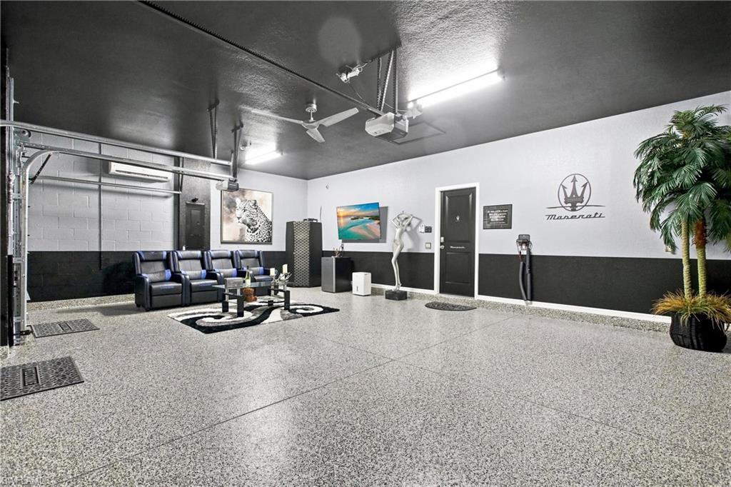 Furnished garage with polished speckled flooring, leather seating, and a Maserati emblem on the wall.