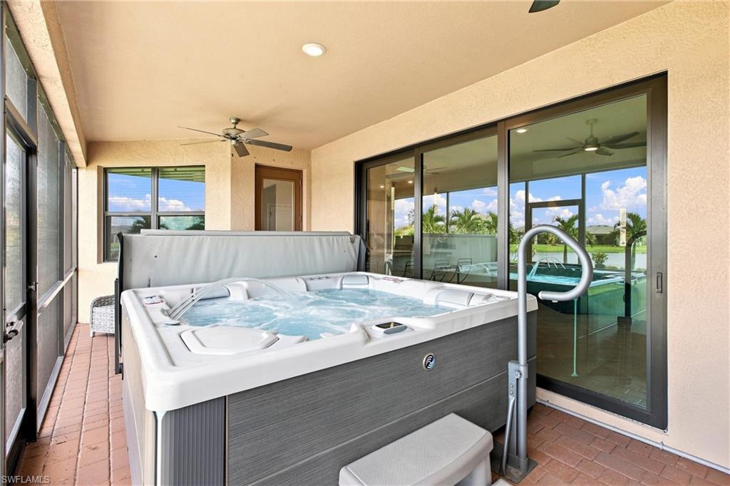Covered patio with a large hot tub and views of the pool and water.