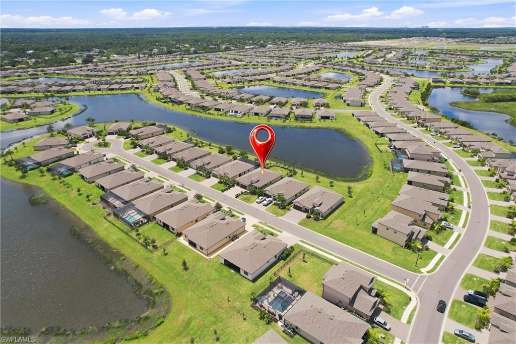 Aerial view of a home beside a pond in a sprawling residential community.