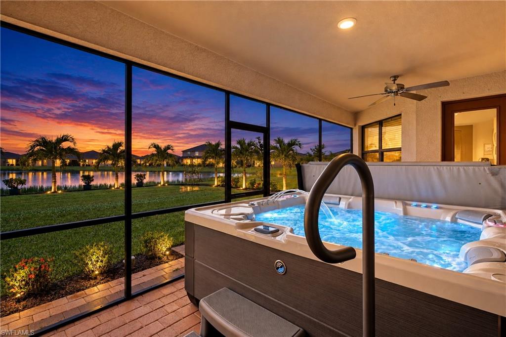 Covered lanai hot tub overlooking a lake and palm trees at sunset.
