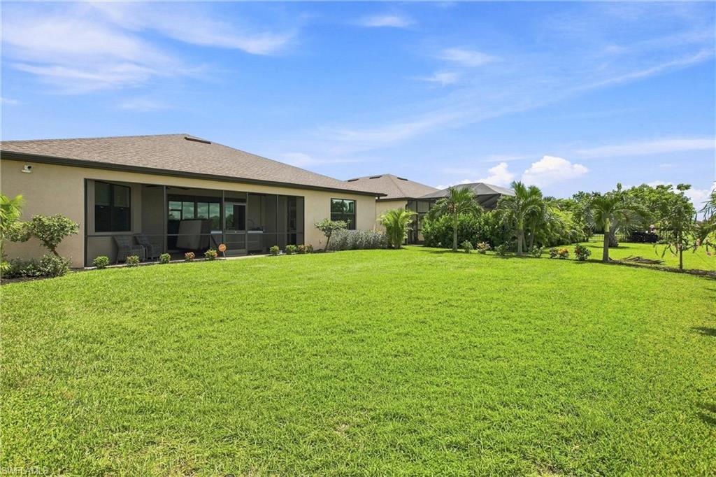 Single-story home with a screened lanai, wide lawn, and palm trees.
