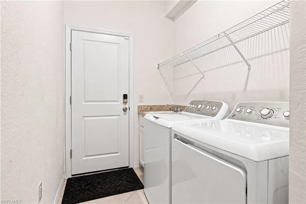 Laundry room with white washer and dryer beneath wire shelving, beside a white door.