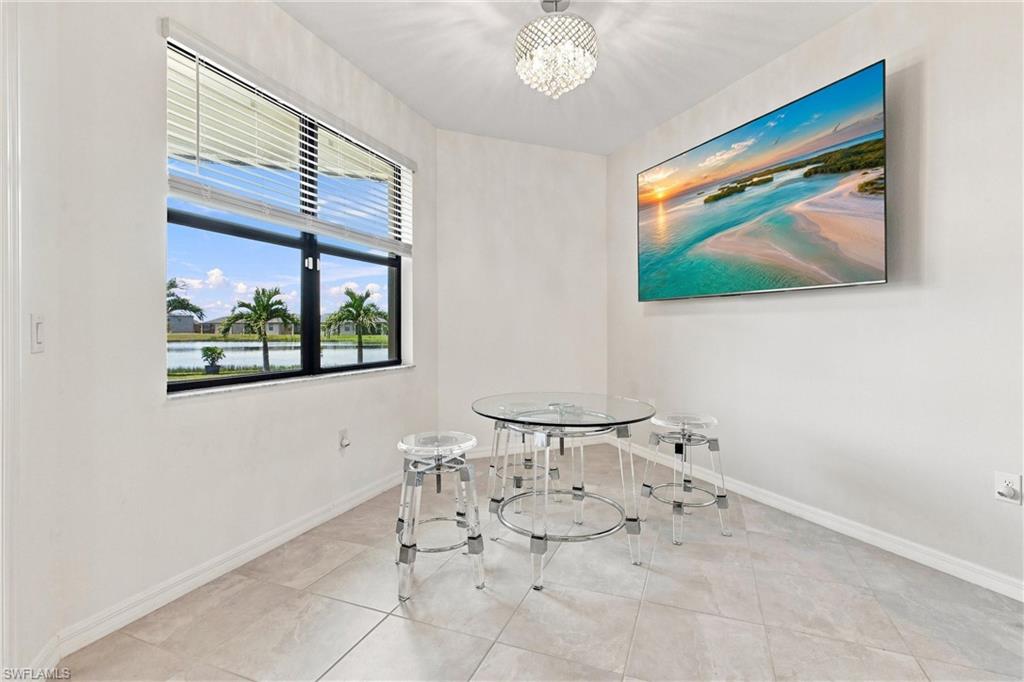 Dining nook with a round glass table and clear stools beside a window overlooking water.