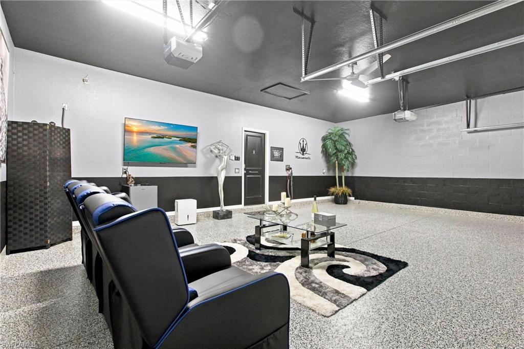 Furnished garage with epoxy flooring, lounge chairs, glass coffee table, and overhead garage door tracks.