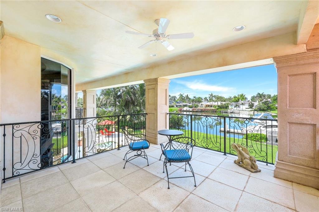 Covered balcony with blue-cushioned chairs overlooking a palm-lined canal.