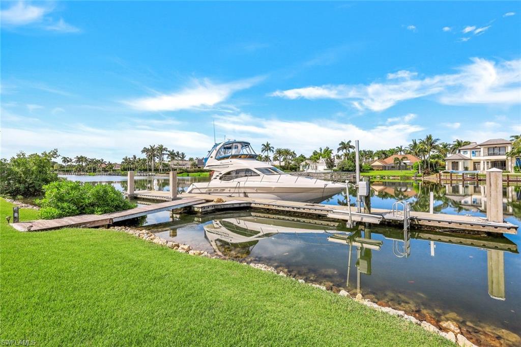 Waterfront lawn with a private dock and yacht on a calm canal.