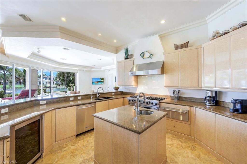 Kitchen with a granite island, stainless steel appliances, and water views through wide windows.
